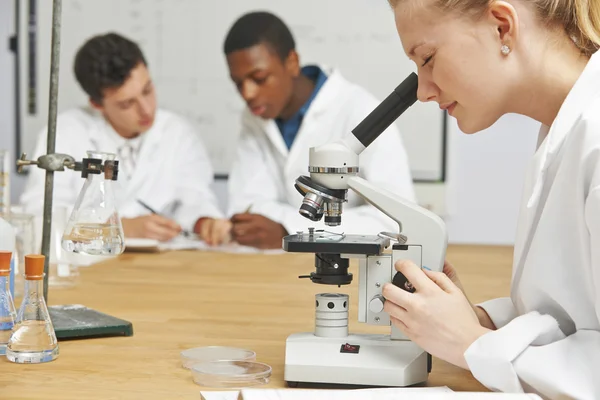 Студенти-підлітки в класі науки за допомогою мікроскопа — стокове фото