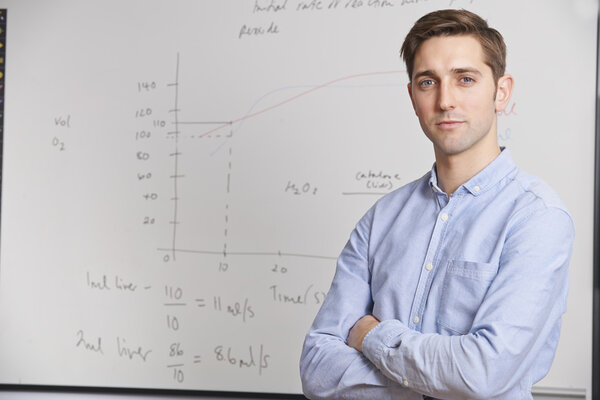 Portrait Of Teacher Standing In Front Of Whitebaord