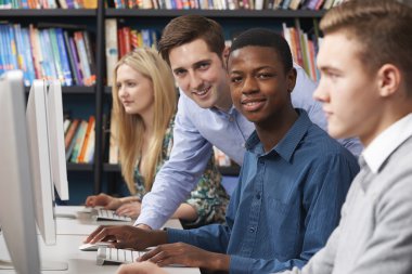 Grup bilgisayarları kullanan genç öğrenci ile öğretmen