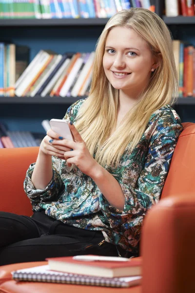 女性青少年学生在图书馆中使用手机 — 图库照片