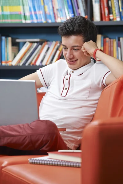 Estudante adolescente masculino com laptop trabalhando na biblioteca — Fotografia de Stock