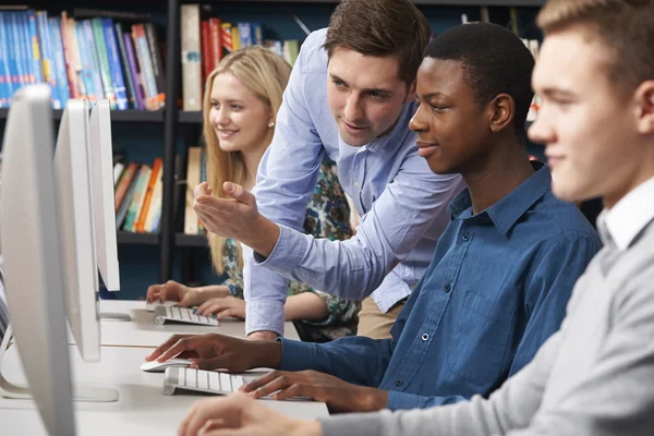 Tutor arbeitet mit einer Gruppe Jugendlicher, die Computer benutzen — Stockfoto