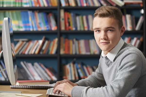 Studente adolescente maschio che lavora in biblioteca — Foto Stock
