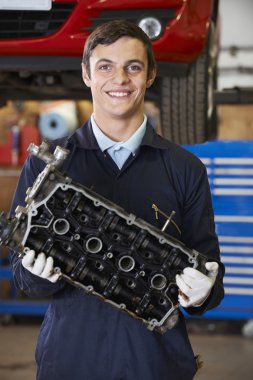 Motor bloğu tutan makinist çırak