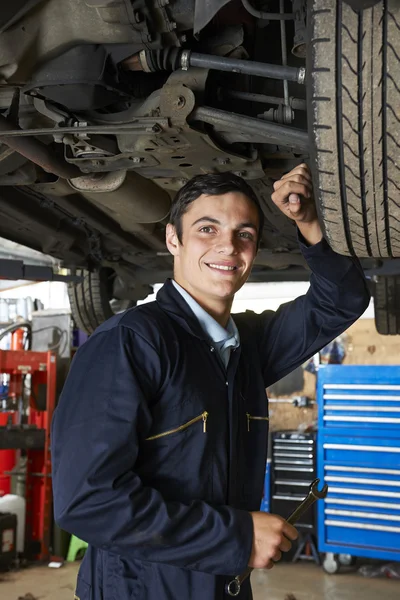 Aprendiz mecânico trabalhando sob carro — Fotografia de Stock