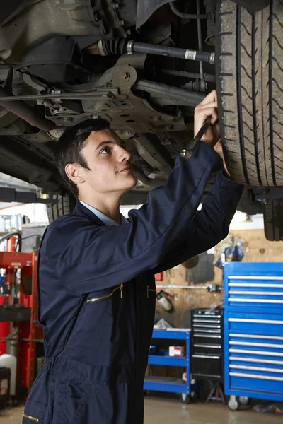 Estagiário mecânico de trabalho sob carro — Fotografia de Stock