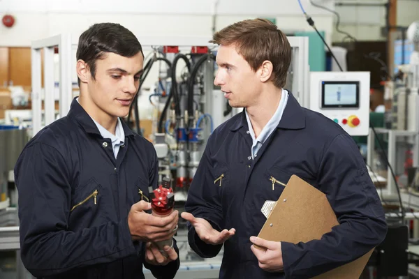 Ingénieur et apprenti discutant d'un composant dans une usine — Photo