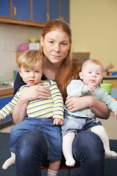 Стрессовая мать с двумя маленькими детьми в Baby Group — стоковое фото