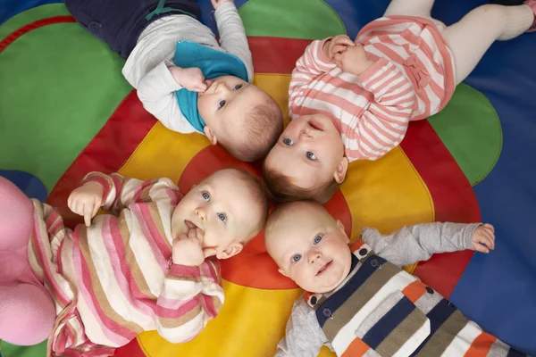 Blick aus der Vogelperspektive auf Babys, die in Spielgruppe auf Matte liegen — Stockfoto