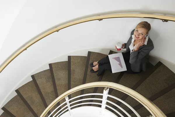 坐在楼梯上的移动电话上的女商人 — 图库照片