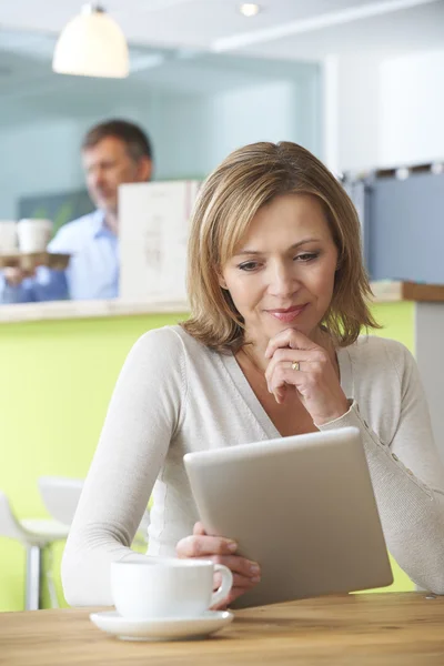 Женщина смотрит на цифровой планшет в кафе — стоковое фото