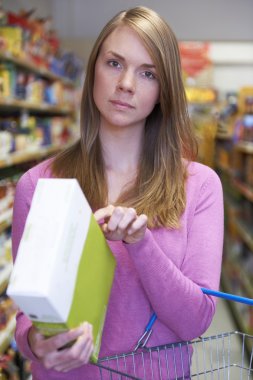 Worried Woman Checking Contents Of Box In Supermarket clipart