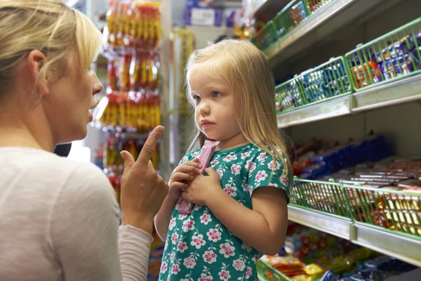 Supermarke でお菓子のカウンターで母と引数を持つ少女 — ストック写真