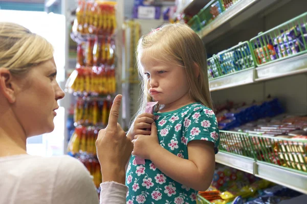 Ребенок спорит с матерью за прилавком конфет — стоковое фото
