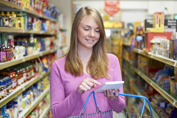 Mulher usando Claculator enquanto faz compras no supermercado — Fotografia de Stock