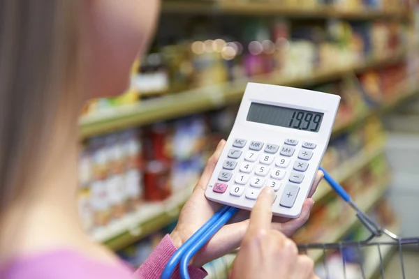 Žena pomocí kalkulačky stát, nakupování v supermarketu — Stock fotografie