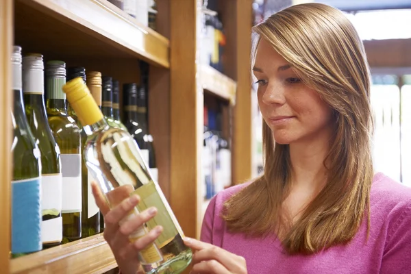 Kvinnan att välja flaska vitt vin i stormarknad — Stockfoto