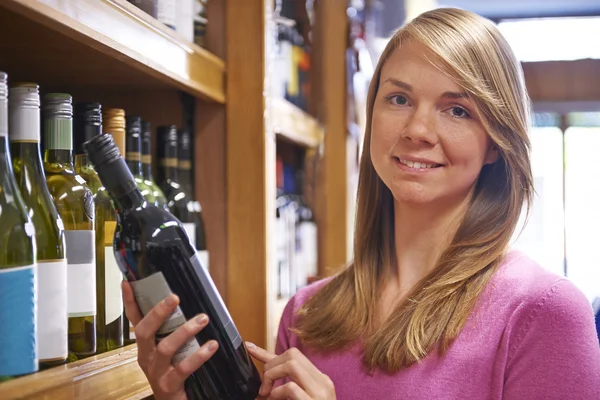 Kvinnan att välja flaska rött vin i stormarknad — Stockfoto