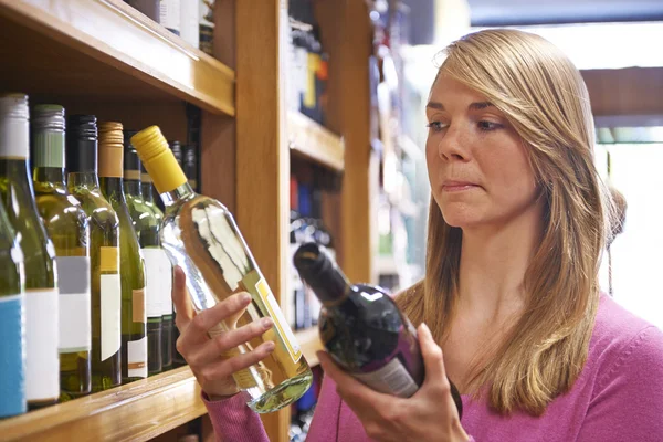 Kvinnan att välja mellan rött och vitt vin i stormarknad — Stockfoto