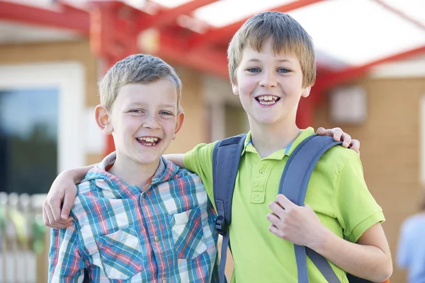 Dois meninos de pé fora da escola com sacos de livro — Fotografia de Stock