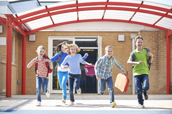 Crianças em idade escolar que correm para o parque infantil no final da aula — Fotografia de Stock