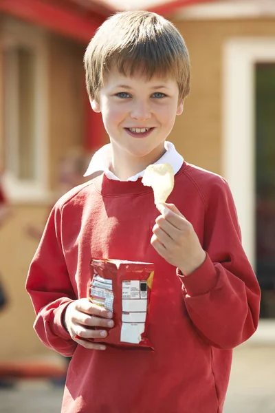 Αγόρι στο σχολείο ομοιόμορφη κατανάλωση πατάτας τσιπ στον παιδότοπο — Φωτογραφία Αρχείου