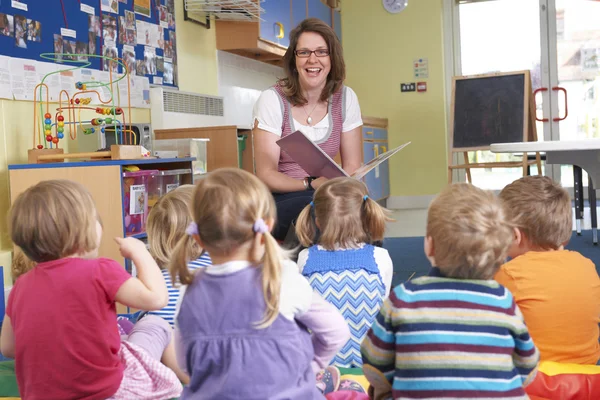 Groupe d'enfants d'âge préscolaire écoutant l'enseignant lire l'histoire — Photo