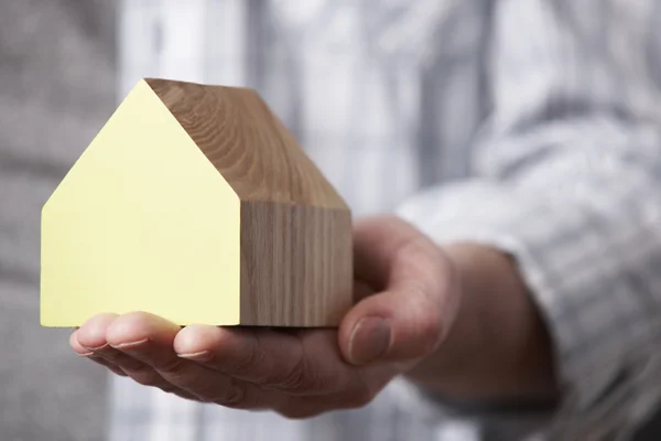 Männliche Hand hält Modell Holzhaus — Stockfoto