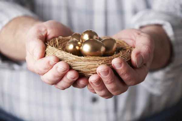 Man håller Nest Full av gyllene ägg — Stockfoto