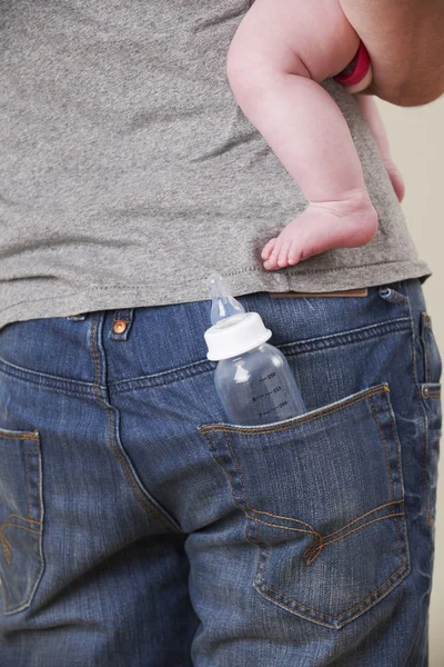 Visão traseira do pai carregando bebê com garrafa no bolso — Fotografia de Stock