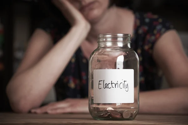 Deprimida mujer mirando tarro etiquetado electricidad — Foto de Stock