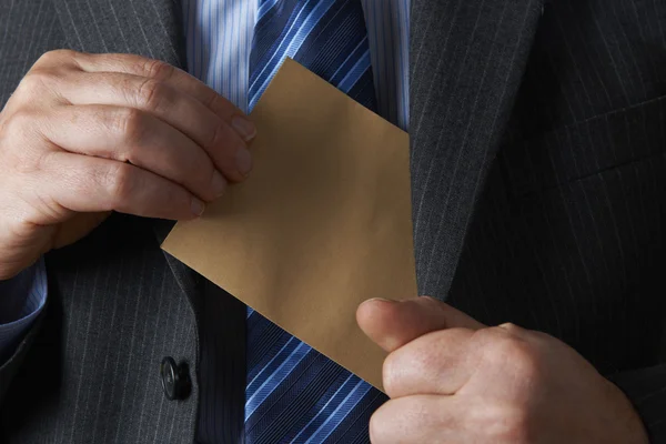 Empresário colocando envelope marrom liso no bolso da jaqueta — Fotografia de Stock