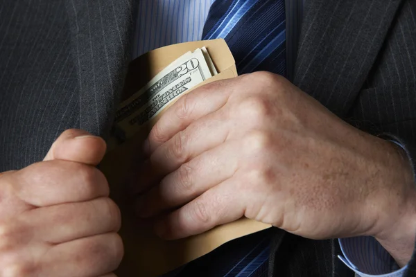 Empresario poniendo sobre de dólares en el bolsillo — Foto de Stock