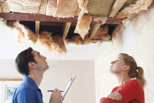 Construtor e cliente inspecionando danos no telhado — Fotografia de Stock