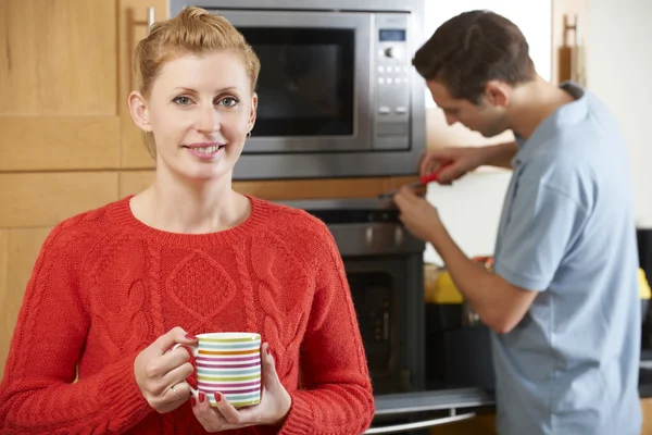 Woman Smiling As Cooker Is Repaired — Stock Photo, Image