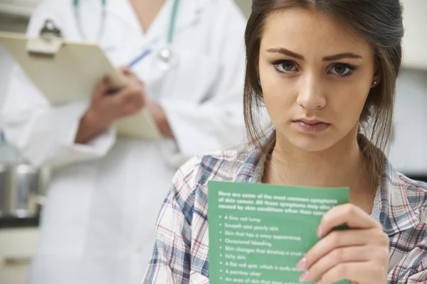 Adolescente chica leyendo folleto en la cirugía del médico — Foto de Stock