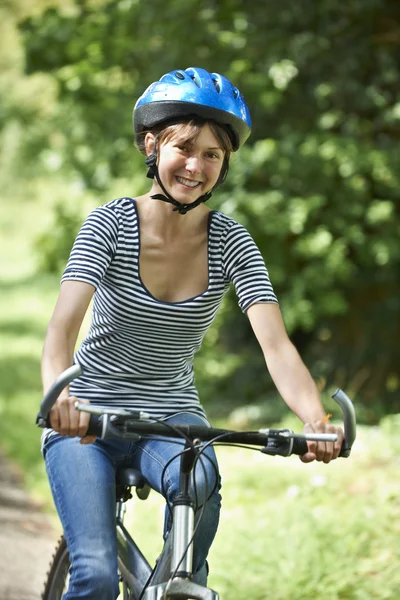 Молодая женщина на велосипеде по сельской дороге — стоковое фото