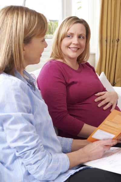 Barnmorska diskutera litteratur med gravid kvinna på hem besök — Stockfoto