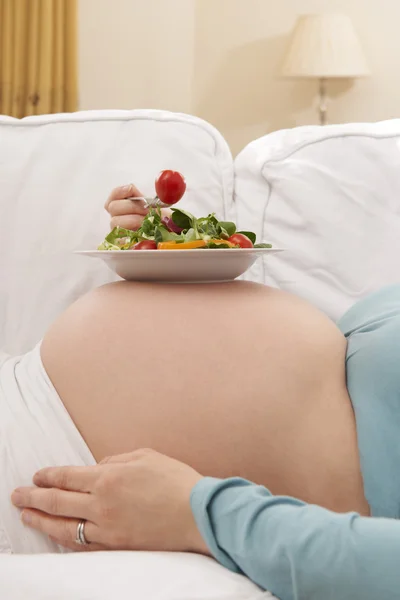 Femme enceinte avec salade saine reposant sur le ventre — Photo