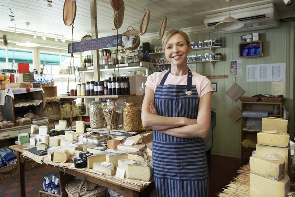 Eigenaar van delicatessen staande in winkel — Stockfoto