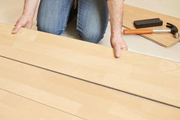 Homem que estabelece piso laminado — Fotografia de Stock