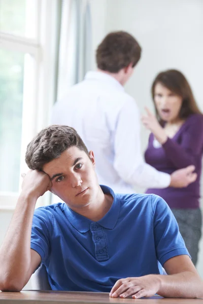 Нещасний хлопчик-підліток з батьками сперечається на задньому плані — стокове фото