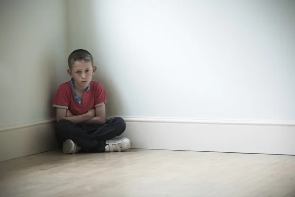 Несчастный ребенок сидит в углу комнаты — стоковое фото