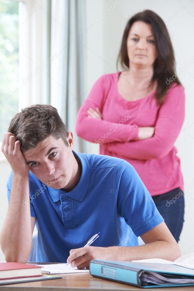 Frustrated Mother Watching Teenage Son Doing Homework