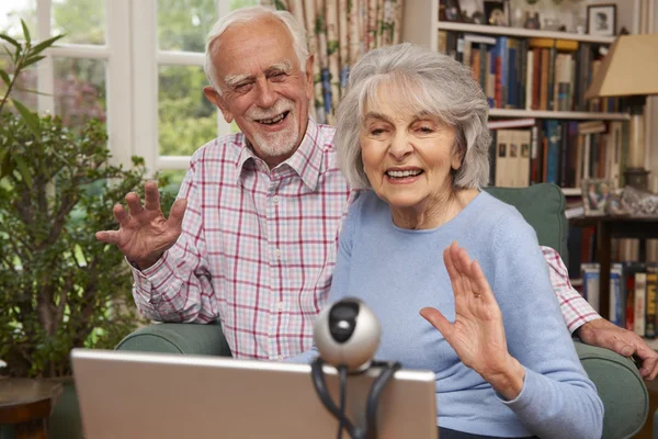 Старша пара використовує ноутбук і веб-камеру для розмови сім'єю — стокове фото