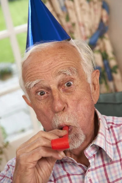 Seniorchef feiert mit Partyhut und Gebläse — Stockfoto