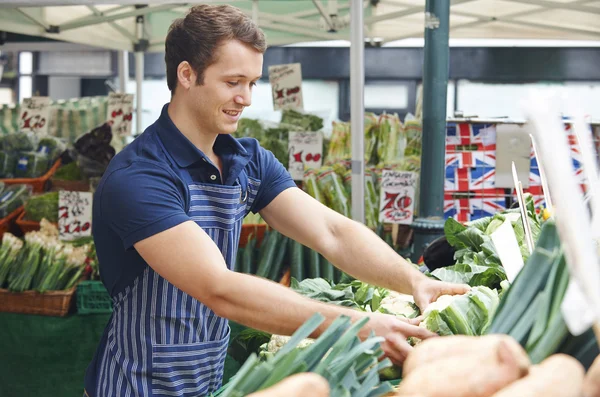 Homme organisant l'affichage sur le marché étal de légumes — Photo