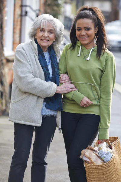 Adolescente ragazza aiutare anziano donna trasportare shopping — Foto Stock
