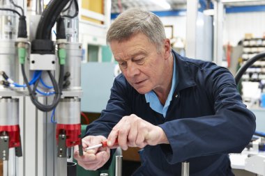 fabrikada makine üzerinde çalışan mühendis