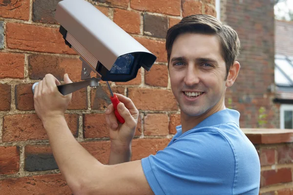 Чоловік встановлює камеру безпеки для стіни будинку — стокове фото